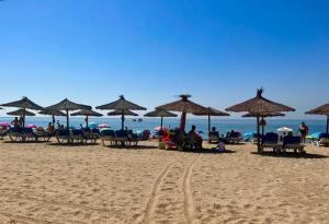 uma praia com guarda-sóis e pessoas sentadas na areia em Tolles Ferienhaus mit Sonnenterrasse direkt am Meer em Isla Cristina