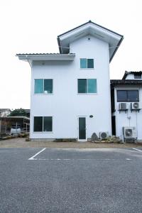 un edificio blanco al lado de una calle en 宿と古道具 iyooo, en Nanao