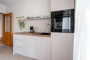 a kitchen with white cabinets and a black appliance at Apartments Lotea in Cavtat +24 photos
