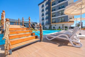 einen Pool mit einer Terrasse mit einem Liegestuhl und einem Sonnenschirm in der Unterkunft Elysium Deluxe Suites Antalya in Antalya
