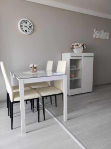 a dining room table with white chairs and a clock at DiP HOME APARTMENTS in Pomorie