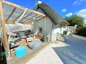 Cette maison au toit de chaume dispose d'une terrasse. dans l'établissement Apb-Spa cottages et Apb BnB avec piscine, à Saint-Jean-de-Monts