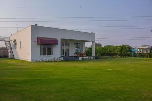 a small white house with a large grass field at The Peace- A Luxury Pool Villa in Jaipur