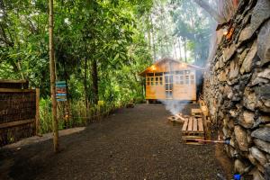 a cabin in a forest with a stone wall at Banana Farm Eco Hostel in Arusha