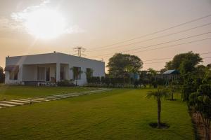 ein Haus auf einem Feld mit einer Palme in der Unterkunft The Peace- A Luxury Pool Villa in Jaipur