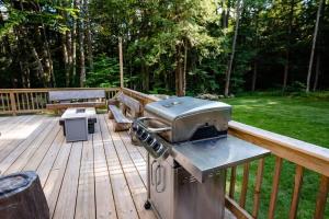 una parrilla en una terraza con mesa de picnic y bancos en Dream Stratton Forest Cabin with Hot Tub and Fast WiFi, en Stratton