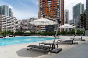 einen Pool mit Sonnenschirmen und Liegestühlen neben einem Gebäude in der Unterkunft Panda Hotel in Hongkong