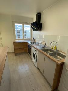 uma cozinha com um lavatório e uma máquina de lavar roupa em Coliving - chambre jaune em Sarcelles