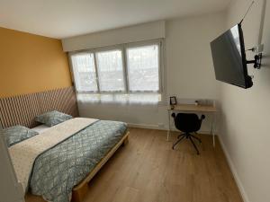 Schlafzimmer mit einem Bett, einem Schreibtisch und einem TV in der Unterkunft Coliving - chambre jaune in Sarcelles