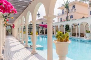 a hotel pool with white columns and pink flowers at The Residence Resort & Villas Phu Quoc in Phu Quoc
