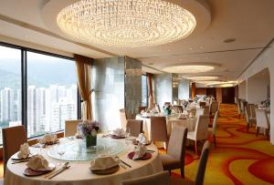 un ristorante con tavoli, sedie e un lampadario di Panda Hotel a Hong Kong