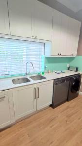 a kitchen with white cabinets and a sink and a dishwasher at Scenic house with splash pool in Cape Town