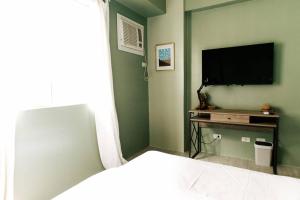 a bedroom with a flat screen tv on a green wall at Siesta Studio in Bacolod