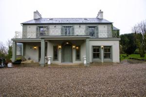 a large white house with a balcony on top at Glenastar Lodge in Newcastle West