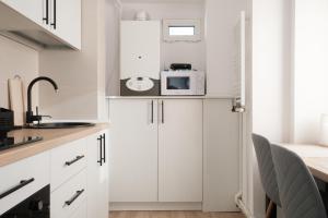 uma cozinha com armários brancos e um micro-ondas em Konstanzer Nicolina12 em Iaşi