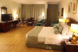 a hotel room with a bed and a living room at Swiss International Al Hamra Hotel in Dammam
