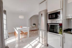 a white kitchen with a table and a refrigerator at Nice House Nina With Jacuzzi in Playa de San Juan