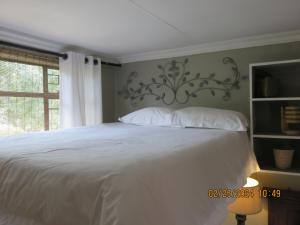 a bedroom with a white bed and a window at Beni Apartment in Pretoria