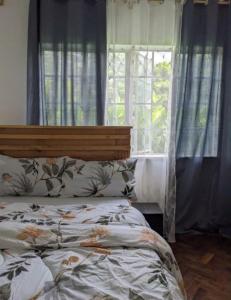 een slaapkamer met een bed en een raam met gordijnen bij WHITE HOUSE GARDEN in Moshi