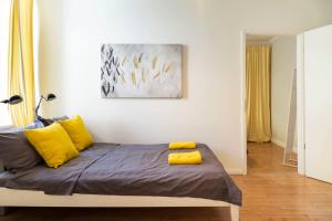 een bed met gele kussens in een witte kamer bij Cosy Two BR plus Self Checkin plus Street Parking in Berlijn