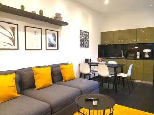 ein Wohnzimmer mit einem Sofa und einem Tisch mit gelben Kissen in der Unterkunft Cosy Studio with Private Parking in Hamburg