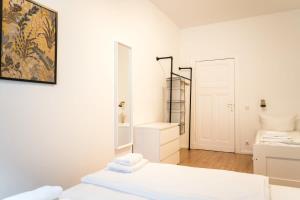 a white room with two beds and a mirror at Great Apartment for Eight in Berlin Neukölln in Berlin