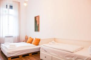 two beds in a room with white walls and orange pillows at Stylish Apartment in convinient location in Berlin