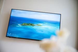 um ecrã de televisão com uma ilha no oceano em Big Central Apartment near Rotkreuzplatz with 3 BR for 12 PAX em Munique