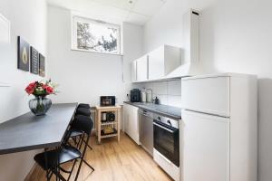 eine Küche mit einem Tisch und einem weißen Kühlschrank in der Unterkunft Big Central Apartment near Rotkreuzplatz with 3 BR for 12 PAX in München