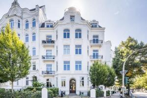 een groot wit gebouw met bomen ervoor bij Charming Apartment in prime location in Hamburg