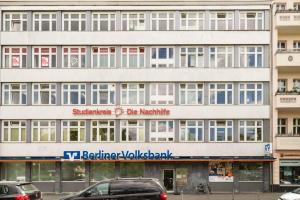 een groot wit gebouw met auto's geparkeerd voor het bij Central Big Apartment Self Checkin in Berlijn