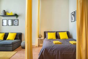 een slaapkamer met een bed met gele kussens en een bank bij Great Apartment close to Kudamm in Berlijn