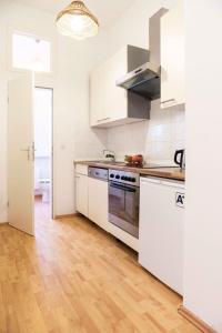 One Bedroom Apartment Berlin Neukölln في برلين: مطبخ بدولاب بيضاء وأرضية خشبية