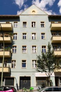 ein großes weißes Gebäude mit einem Baum davor in der Unterkunft One Bedroom Apartment Berlin Neukölln in Berlin