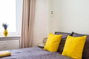 1 cama con almohadas amarillas en un dormitorio en Cosy Three BR Two BTH plus AC plus Self CheckIn plus Street Parking, en Berlín