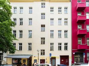 um edifício branco alto com vermelho em Cosy Three BR Two BTH plus AC plus Self CheckIn plus Street Parking em Berlim