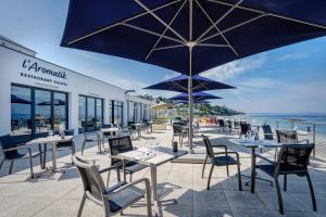 un patio extérieur avec des tables, des chaises et des parasols dans l'établissement Hôtel Valdys Thalasso & Spa - l'Escale marine, à Douarnenez