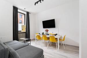 a living room with a dining room table and yellow chairs at 90m2 für bis zu 12 Personen - München Innenstadt in Munich