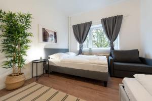 een slaapkamer met een bed, een bank en een raam bij Apartment 2 Hamburg Winterhude in Hamburg