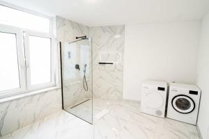 a white bathroom with a shower and a washing machine at Hamburg Gem for 12 in Hamburg