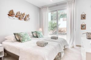 a white bedroom with two beds and a window at Marina Luah in Benissa +26 photos