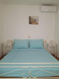 a bedroom with a blue bed with two tables at Apartments Jaca in Rab