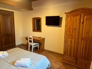a bedroom with a bed and a desk with a television at La corte dell'ulivo in Polazzo