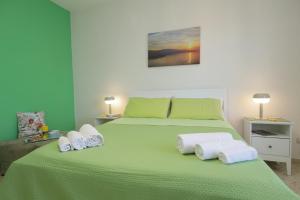 una camera da letto con un letto verde e asciugamani di La Coccinella Sorrento a Sorrento