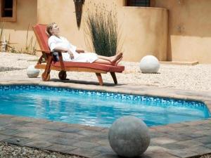 una donna seduta su una sedia accanto alla piscina di Bydand Guest House ad Addo