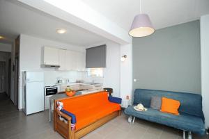 a living room with a blue couch and a kitchen at See to Sea Apartments 2 in Paralia Dionysiou