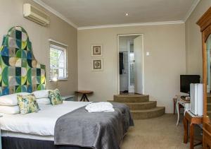 a bedroom with a bed and a tv and stairs at Via's Guesthouse in Greyton