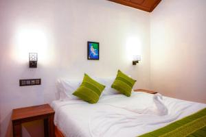 a bedroom with a white bed with green pillows at Coorg Mystere - Luxury Homestay in Madikeri