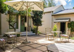 a patio with a table and chairs and an umbrella at Via's Guesthouse in Greyton