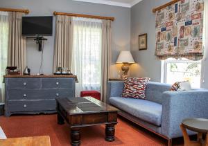 a living room with a blue couch and a dresser at Via's Guesthouse in Greyton